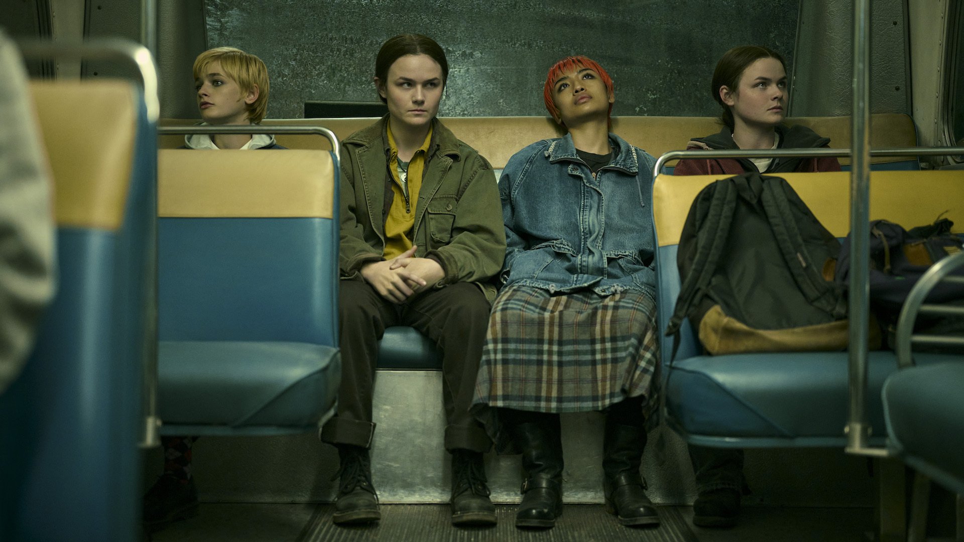 Four students sit at the back of a bus.