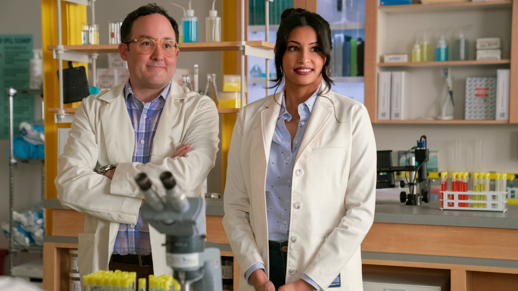 Two people in lab coats stand in a lab.
