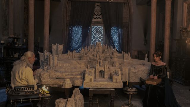 Viserys and Alicent sitting in chairs with a massive model of Old Valyria on the table between them