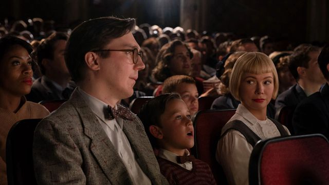 Young Sammy (Sammy (Mateo Zoryon Francis-DeFord) gapes in wonder at the movies, sitting between his father Burt (Paul Dano) and mother Mitzi (Michelle Williams), who share a knowing smile over his head in The Fabelmans