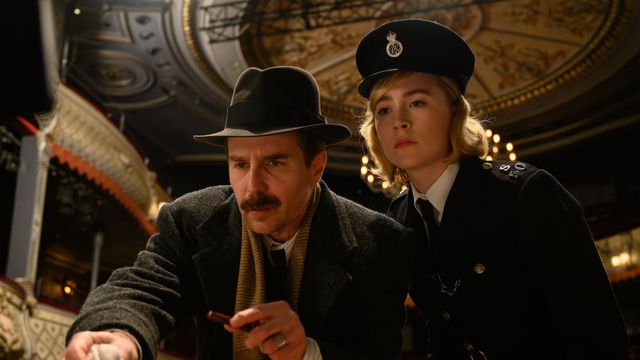 In a grand theater, Inspector Stoppard (Sam Rockwell, in a fedora) and Constable Stalker (Saoirse Ronan, in uniform) examine a clue