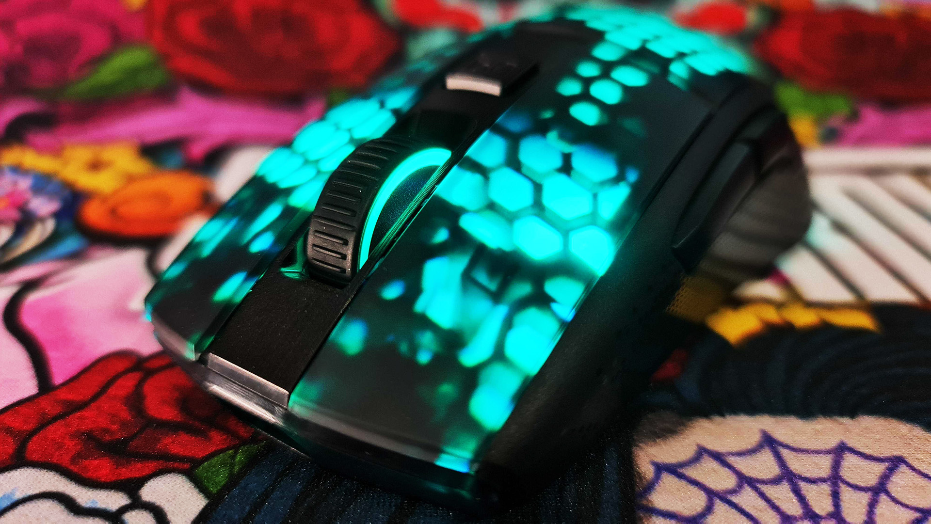 Roccat Burst Pro Air gaming mouse with RGB LEDs enabled on colourful deskmat.