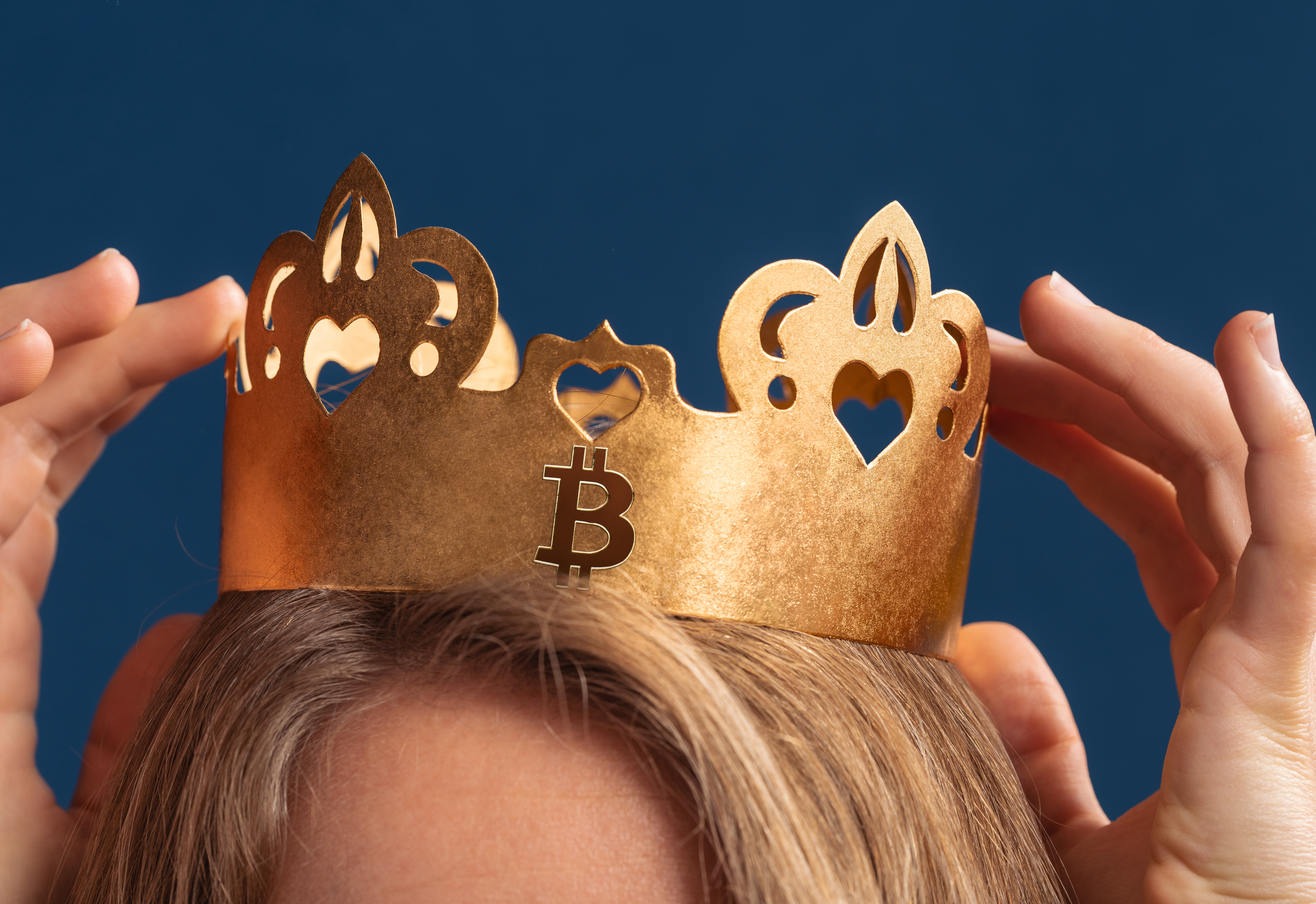 a woman's hands and the top of her head as she touches her crypto crown