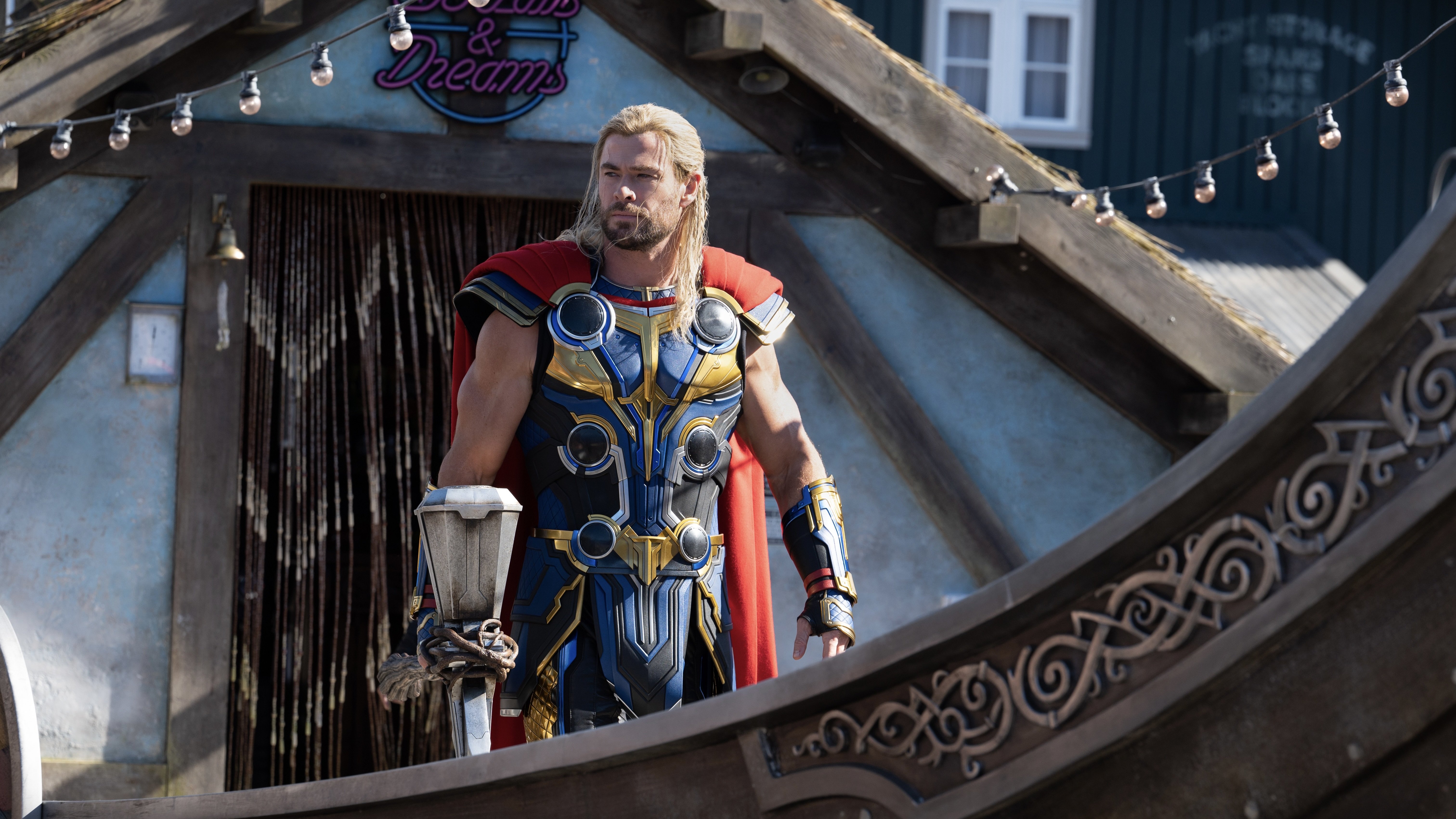 Thor, a muscly blonde man in red and blue armor carrying a hammer, stands at the front of a Viking boat.
