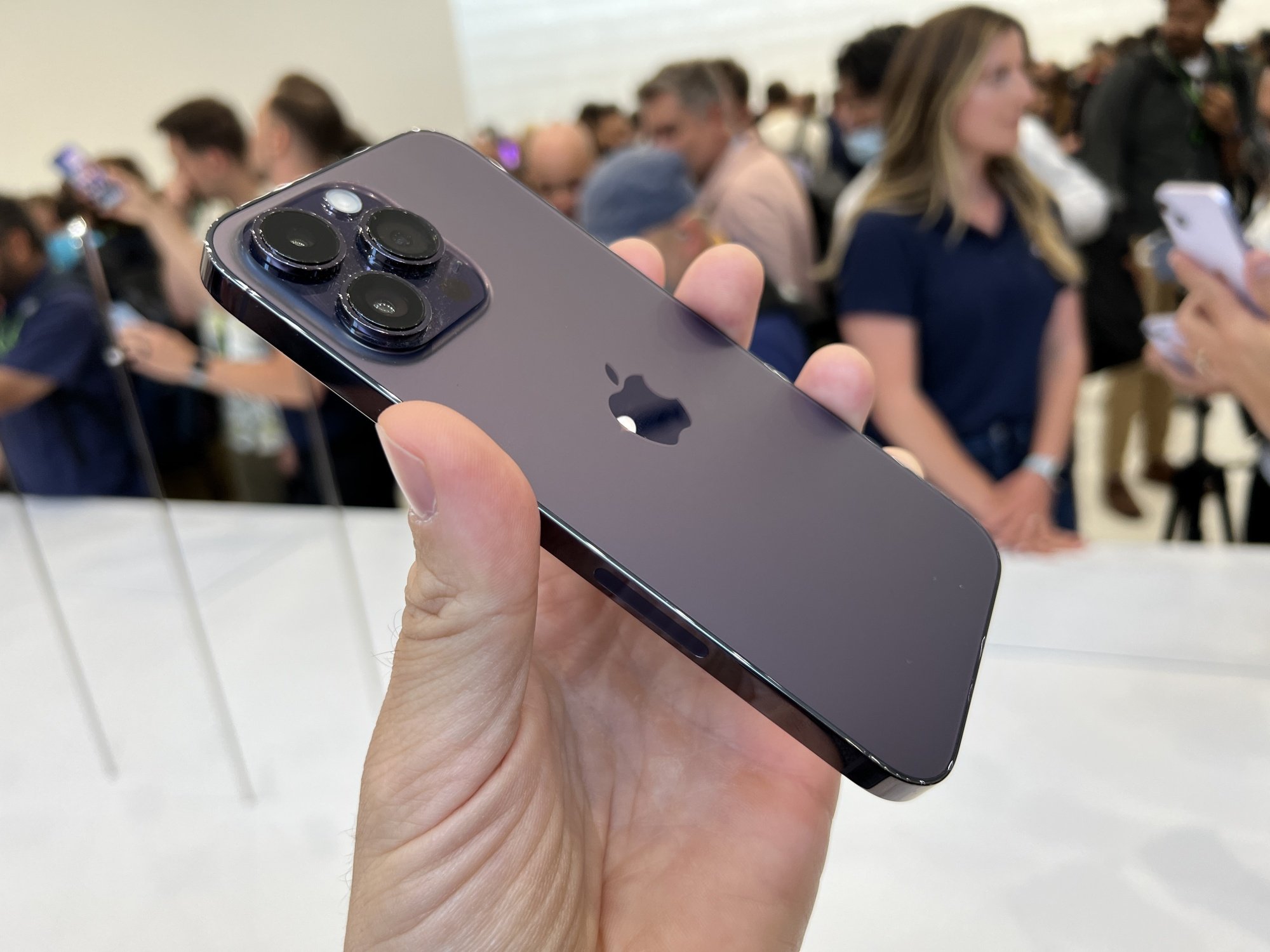The iPhone 14 Pro, seen from the back, held aloft by a single hand.