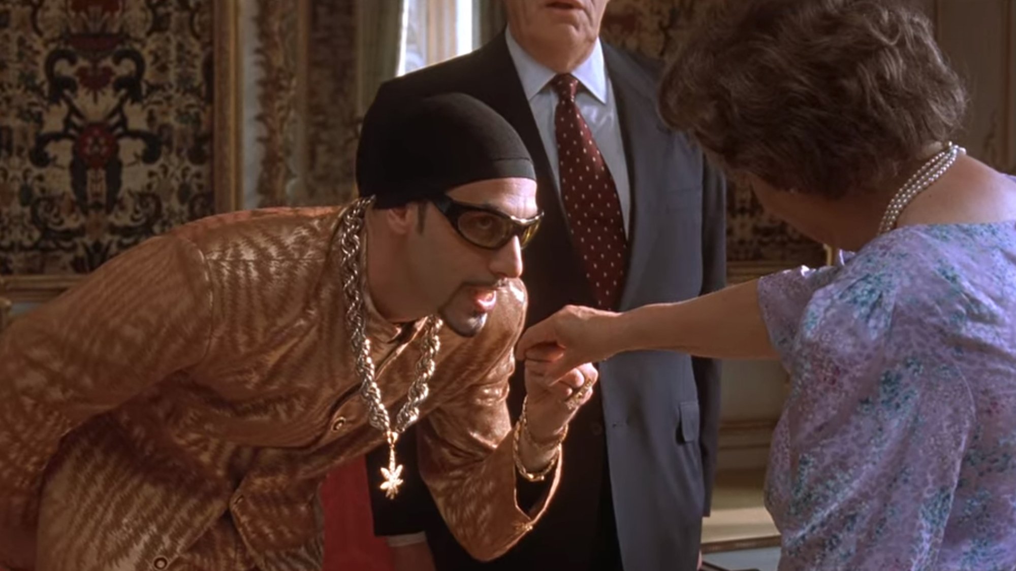 The character Ali G holds an actor's hand who looks like the Queen.