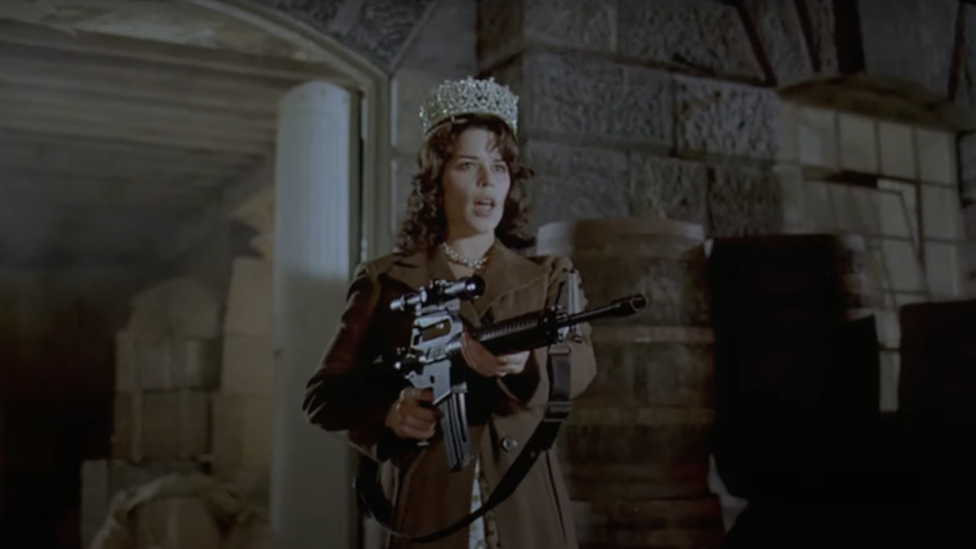 An actor dressed up as Queen Elizabeth II with a machine gun.