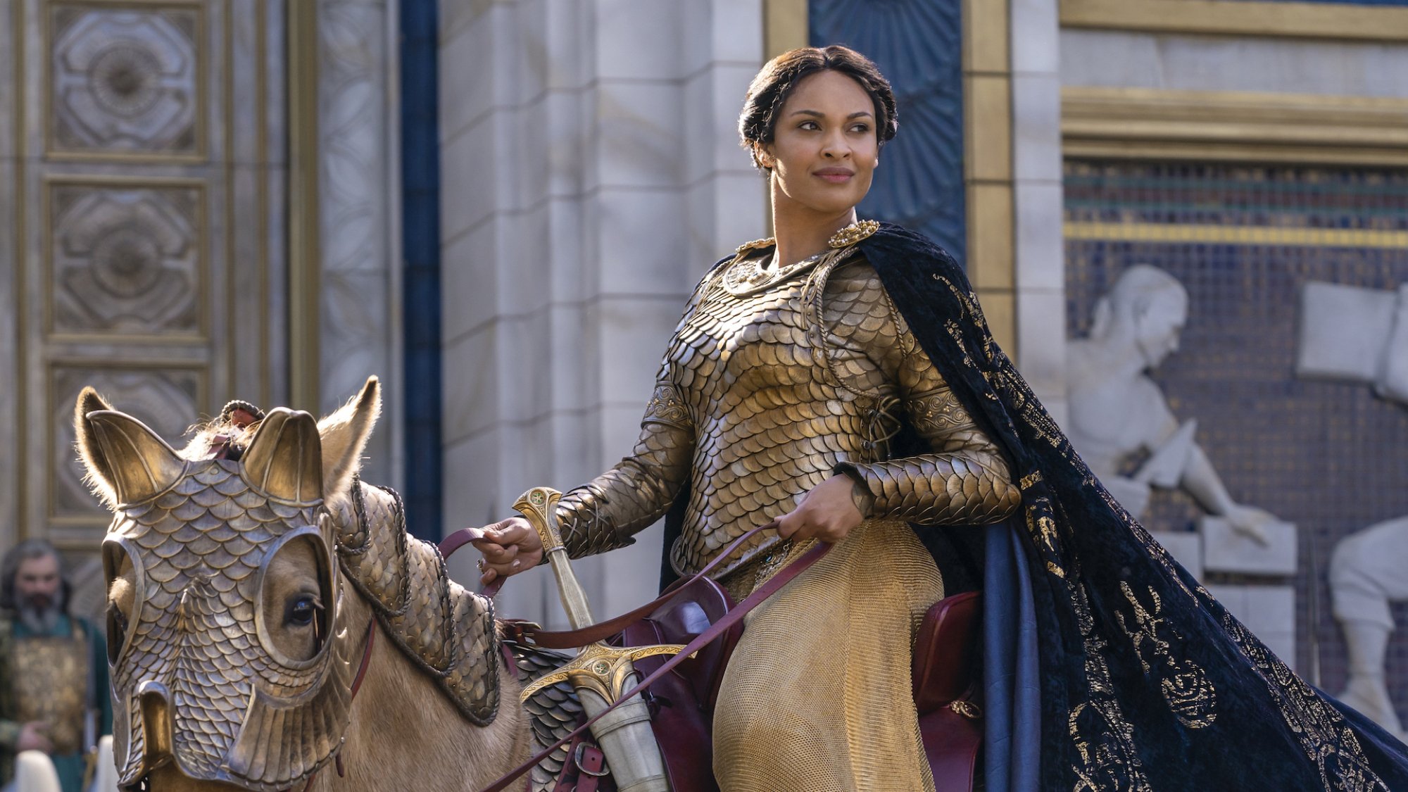 A woman in golden armor rides a horse in golden accoutrements.