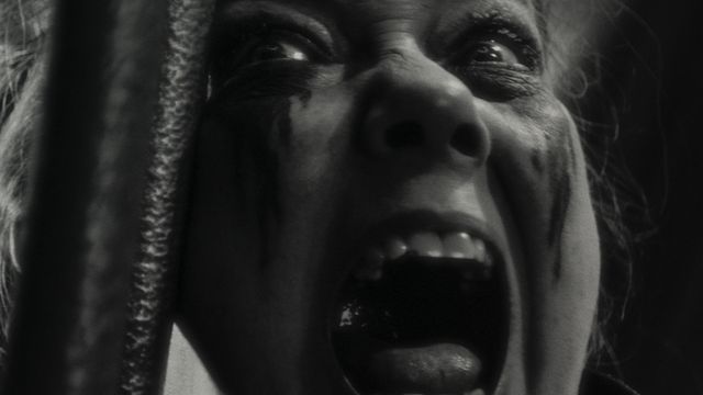 Verussa (Harriet Sansom Harris), face streaked with ritual makeup, screams in extreme closeup in Marvel’s Werewolf By Night