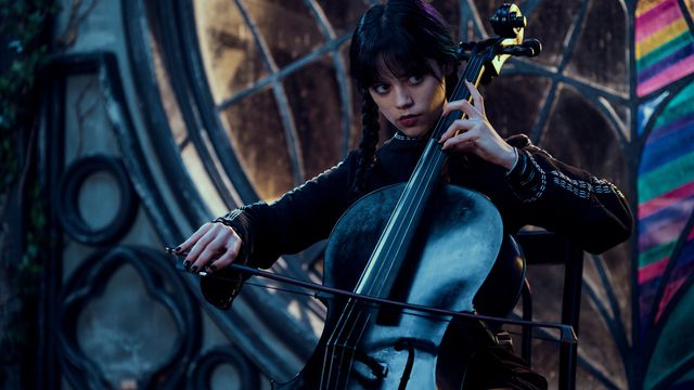 a dark-haired goth-dressed Wednesday plays the cello