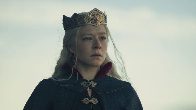 Emma D’Arcy in HBO’s House of the Dragon as Rhaenyra Targaryen stands in a cloak with a golden crown on her head