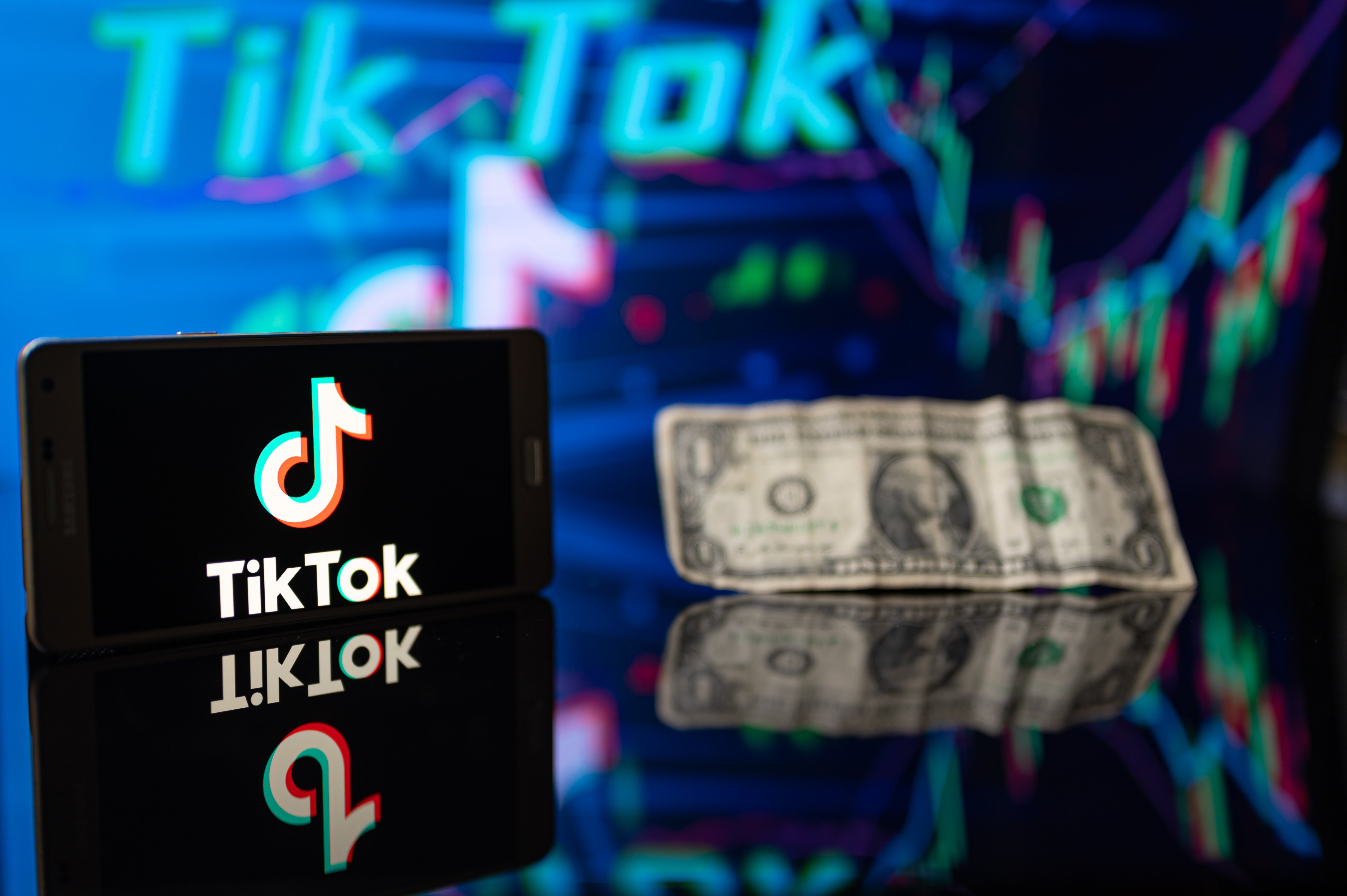 a smartphone showing the TikTok logo, and a dollar.
