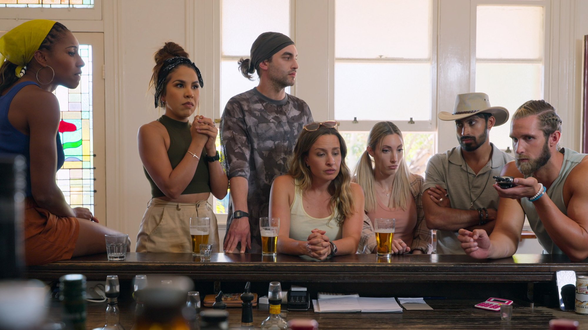 A group of people sit at the bar in a pub.