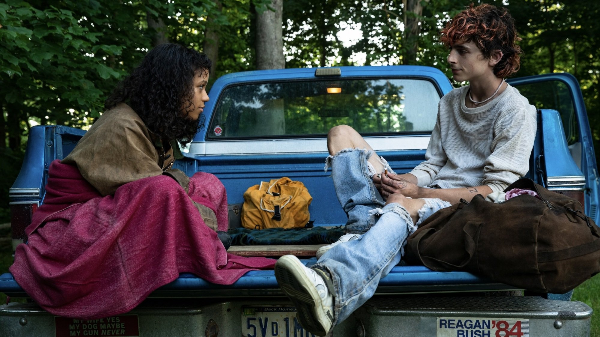 A young man and woman sit in a truck bed.