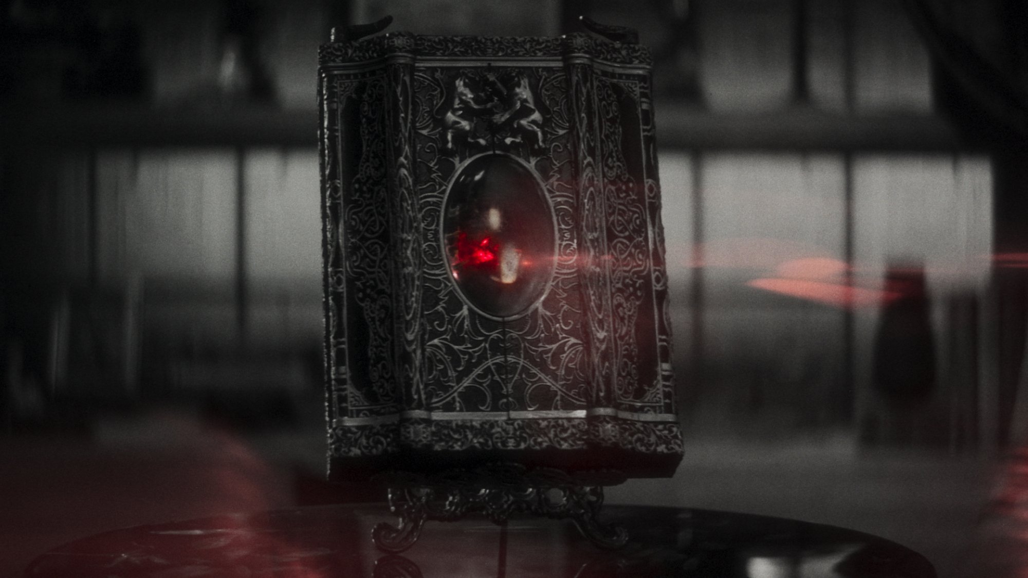 A black and white film still showing a red glowing stone in an elaborate case.