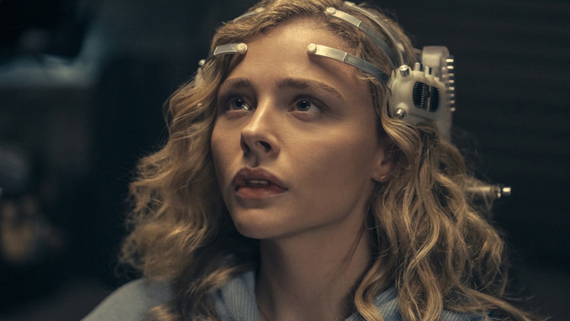 A blonde woman wears a futuristic headset.