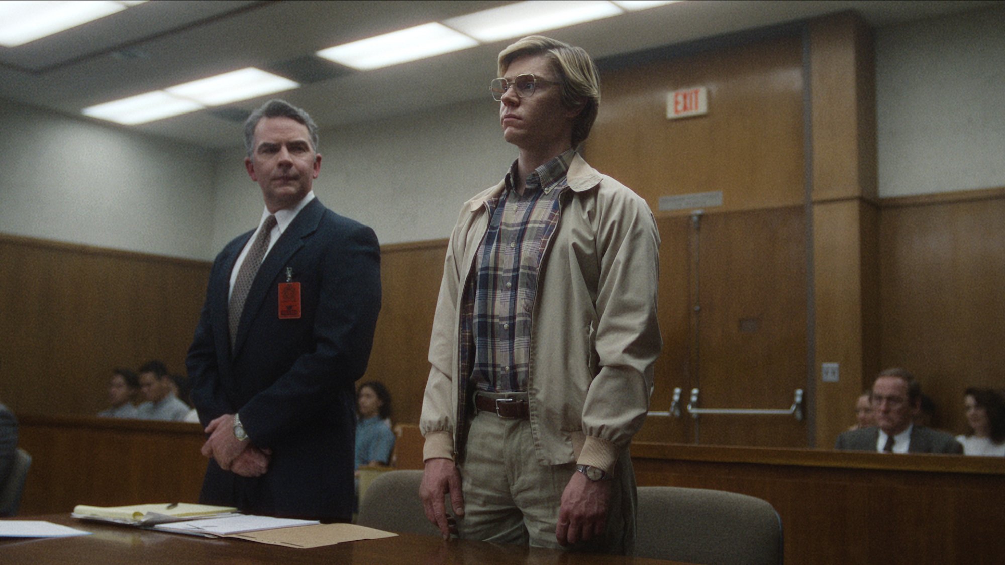 Two men stand in a courtroom, a lawyer and a defendant.