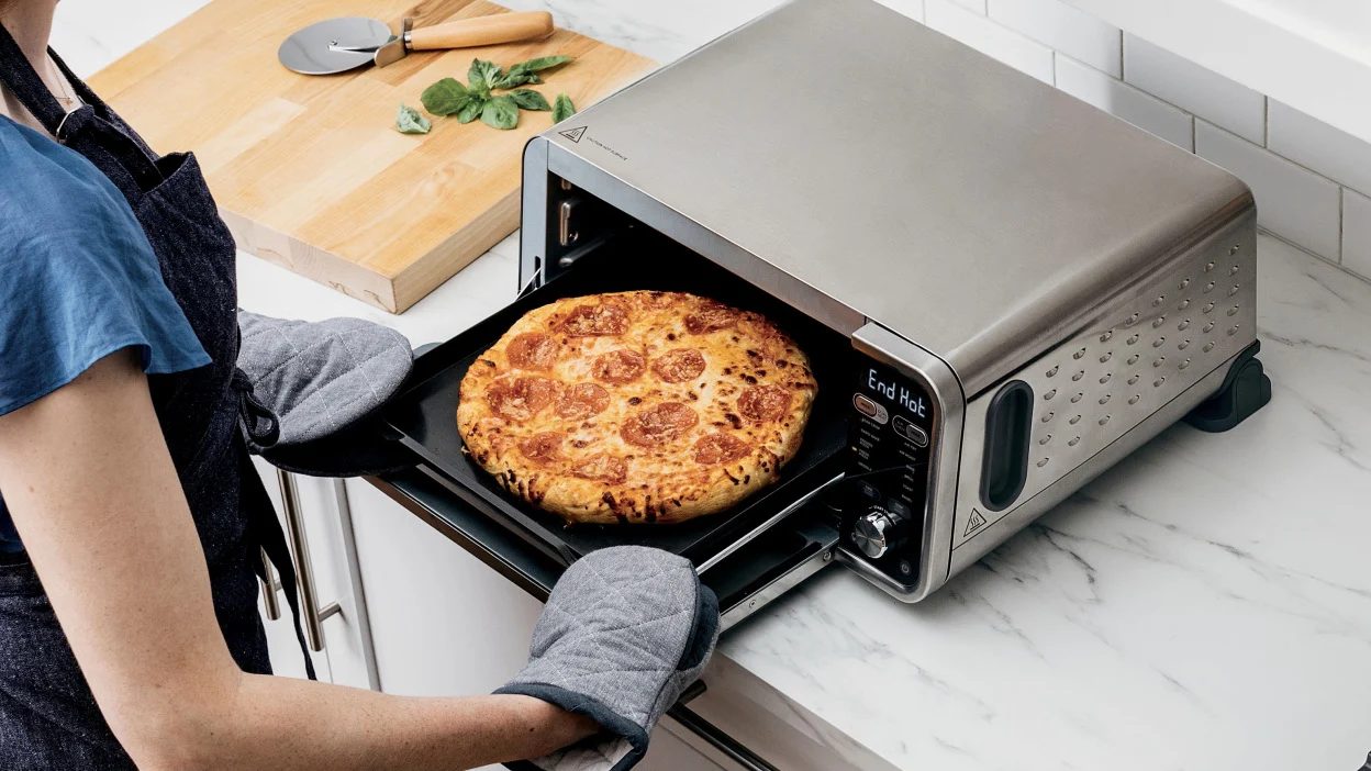 Person taking pizza out of Ninja Foodi toaster oven and air fryer