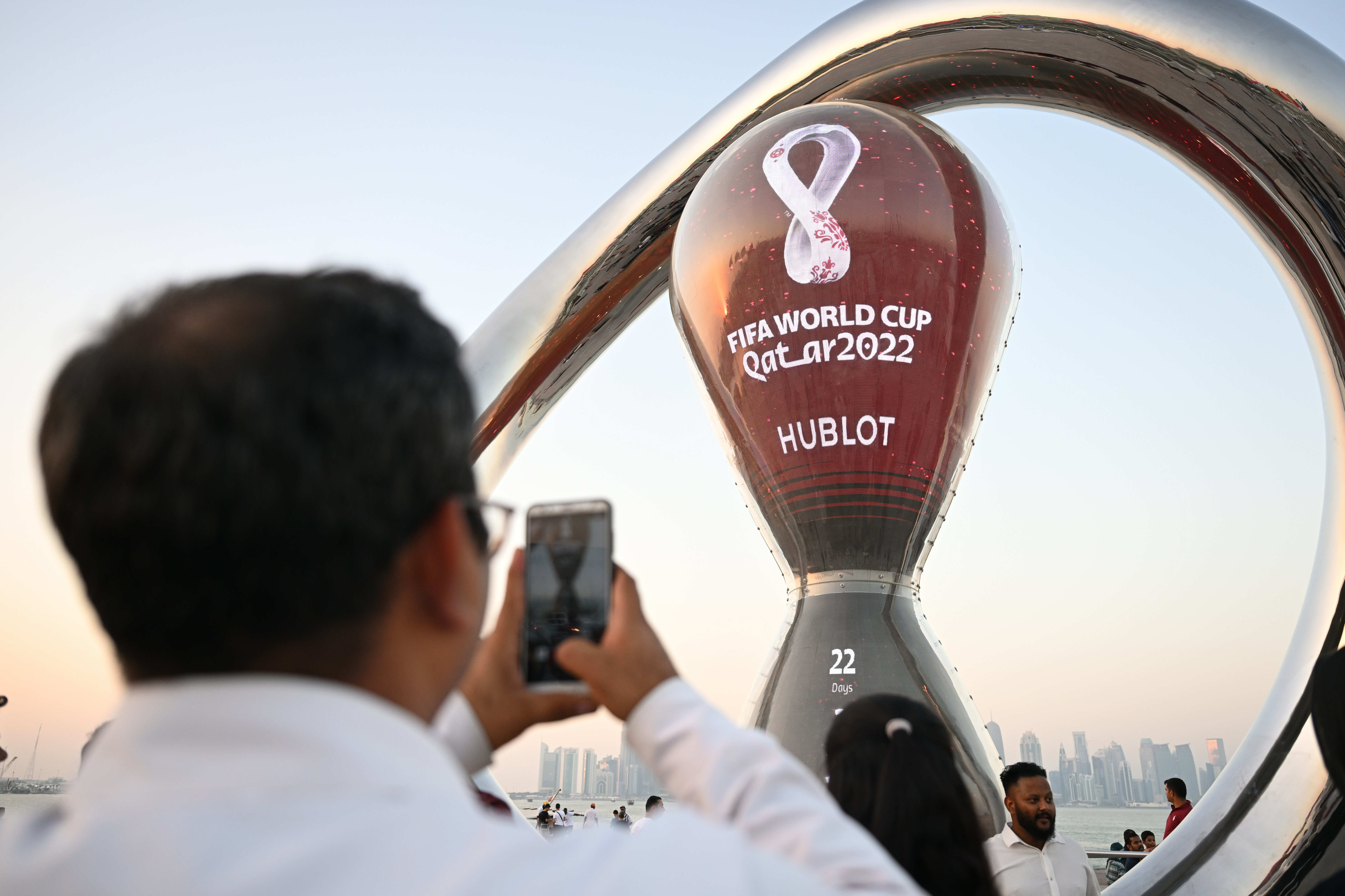 A man holds up his phone to take a picture of a giant World Cup countdown clock. 
