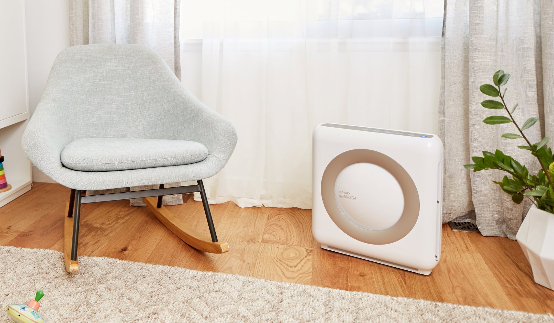 Coway Airmega air purifier in bedroom beside plant and chair