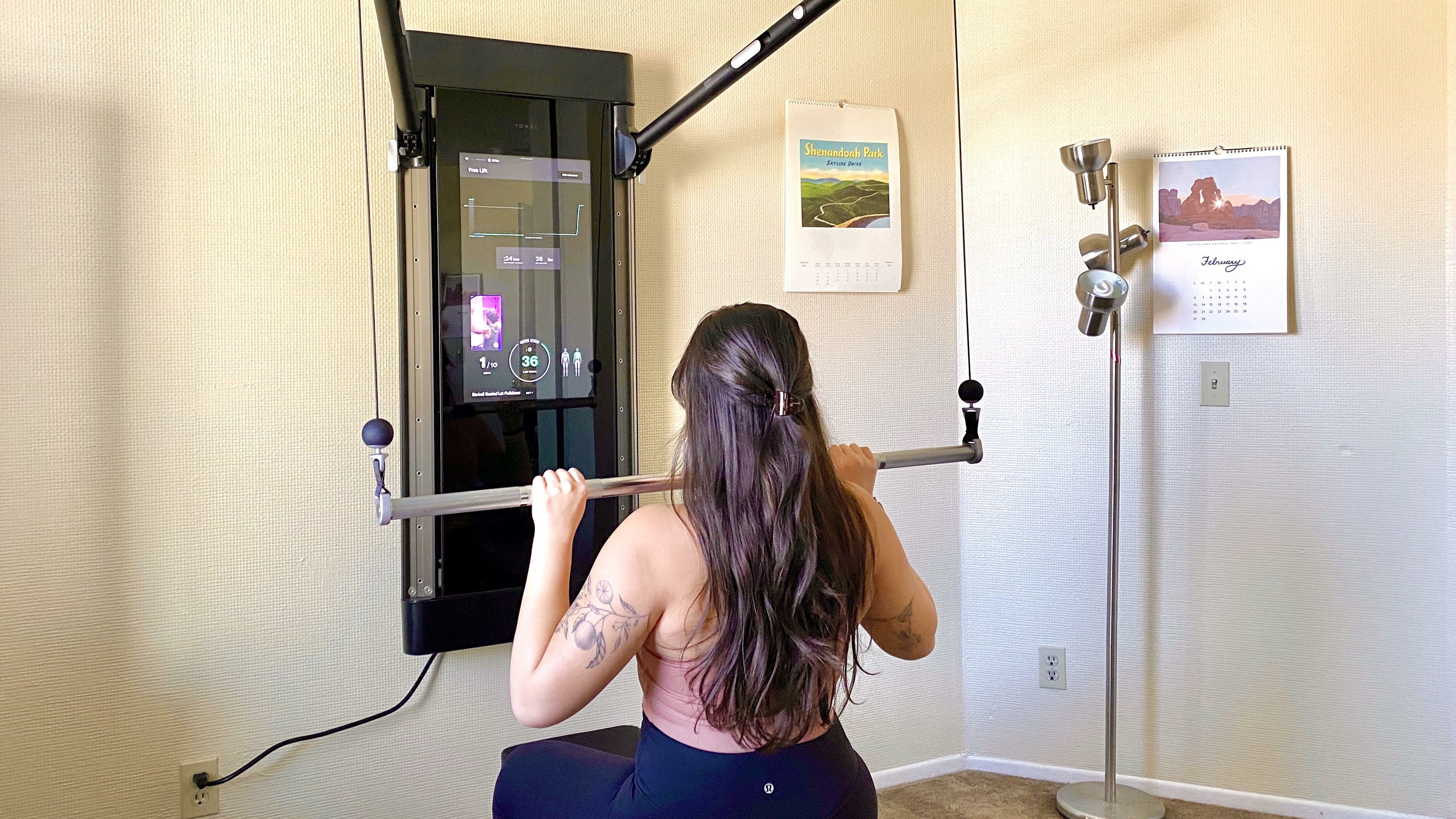 Person with long hair using Tonal to do a lat pulldown