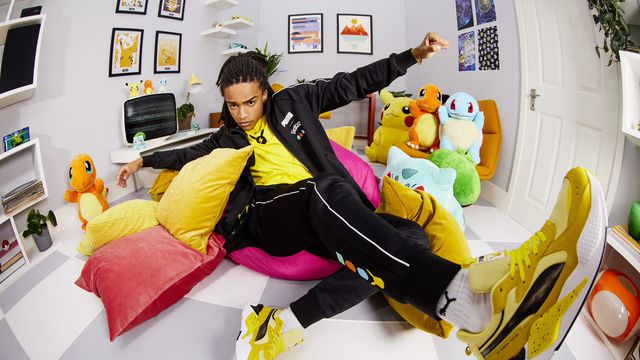 A photo of a person wearing the Puma Pikachu sneakers. The image using a fish-eye lens as the model leans back with their arms held open. 