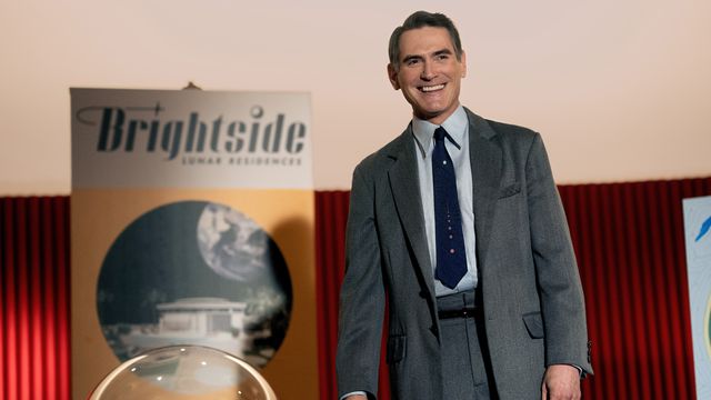 Retro-future salesman Jack (Billy Crudup) stands onstage in front of a poster advertising timeshares on the moon in Hello Tomorrow!