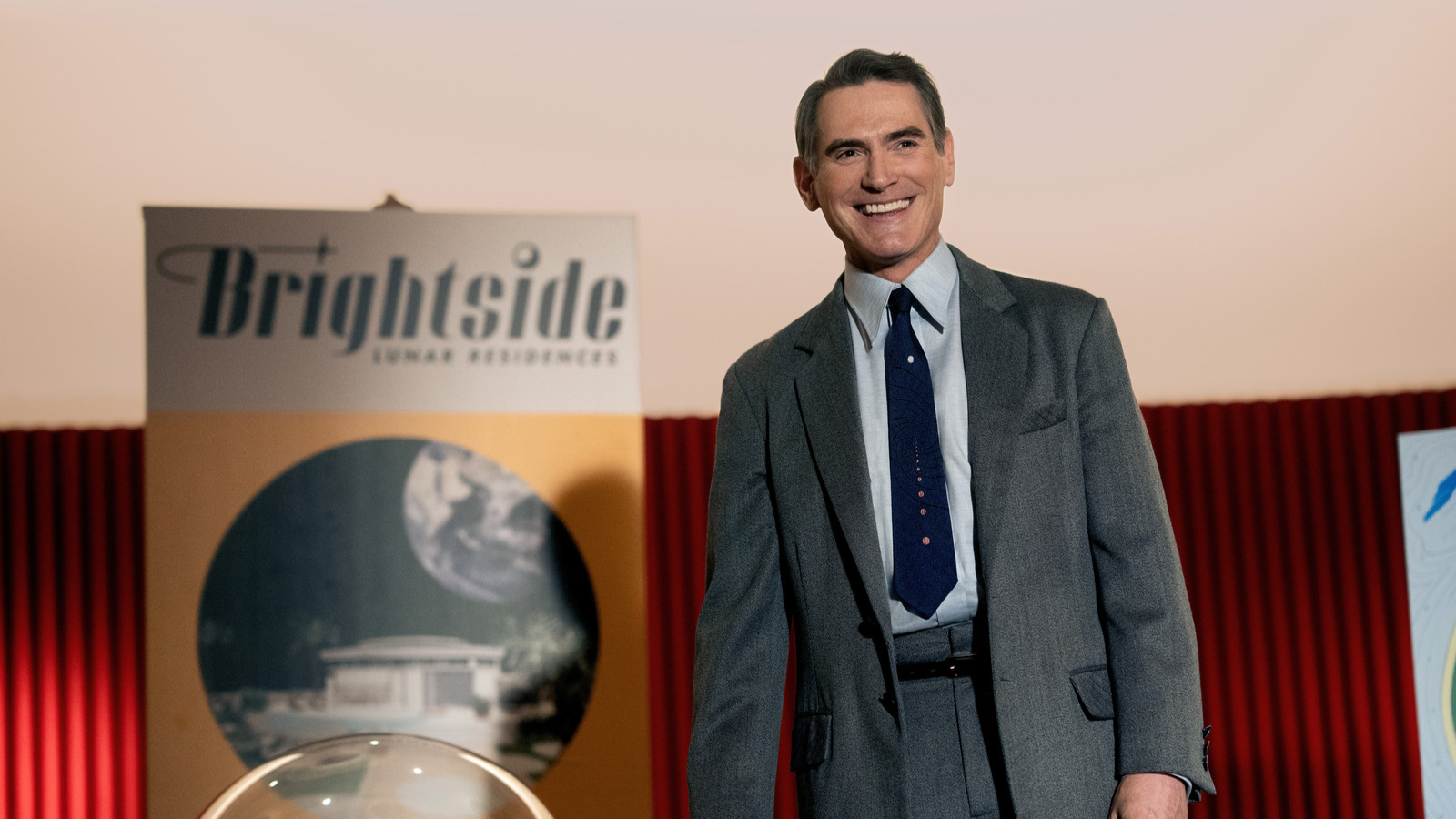 A man in a suit stands in front of a billboard promoting space travel. 