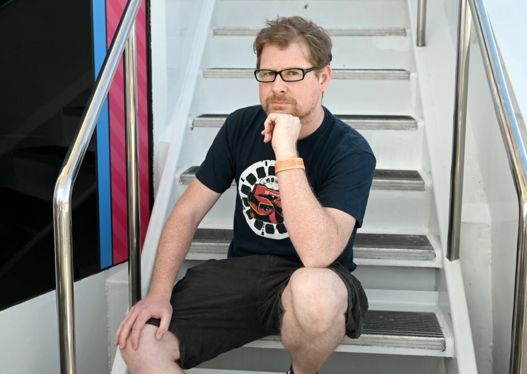 Justin Roiland sitting on a set of stairs.