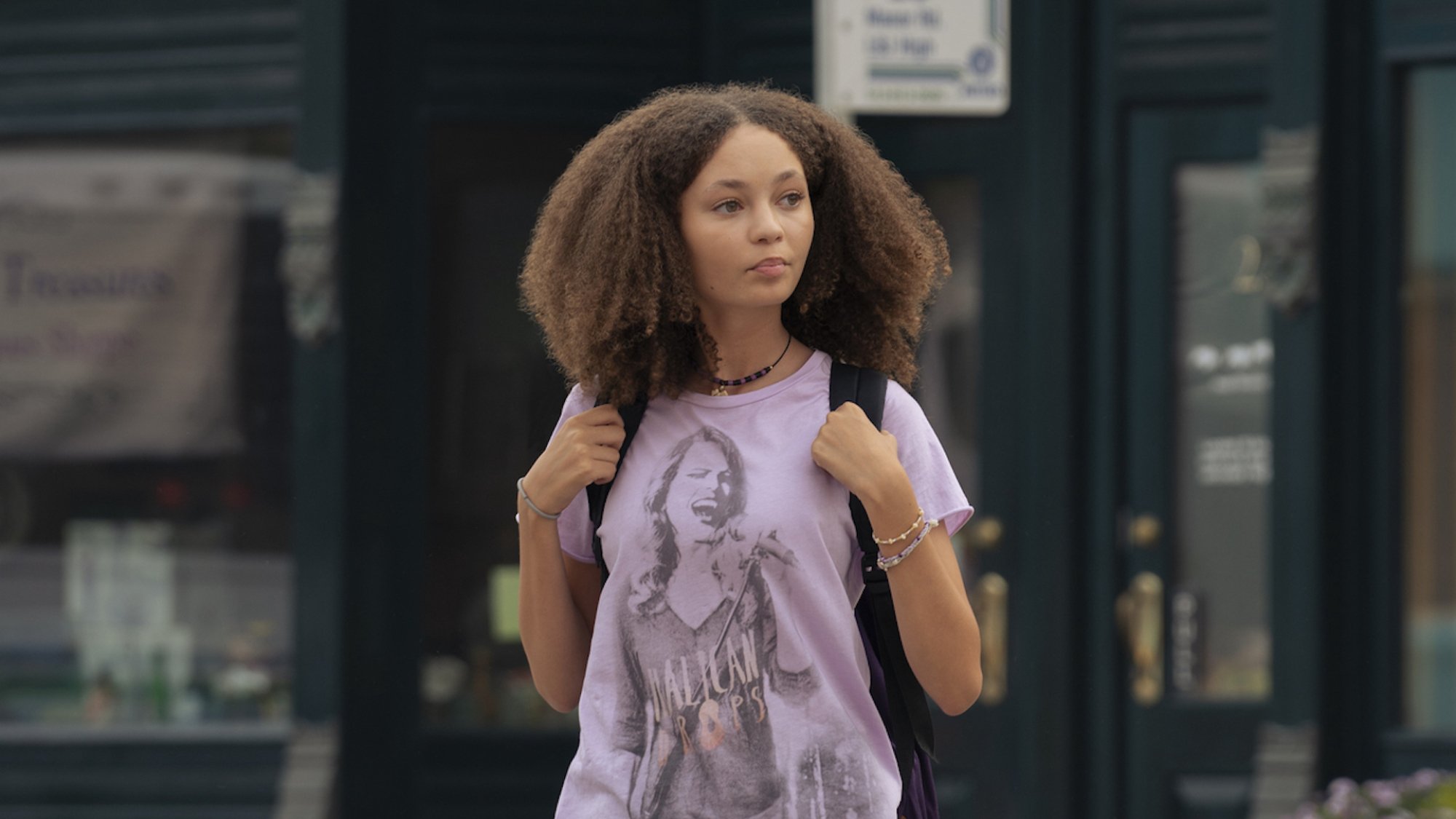 A teen wearing a backpack walks through a small town.